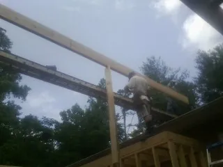 Carpenter setting a ridge beam over a new addition frame — Ice Dam Removal by Roofing Brothers in Pike Road