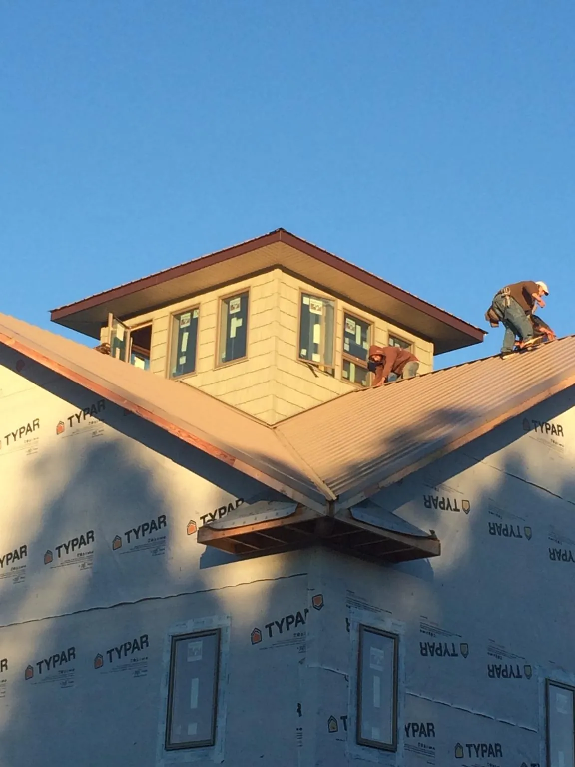 Roofers working around a rooftop cupola on a new metal roof at sunset — Roof Waterproofing in Pike Road by Roofing Brothers
